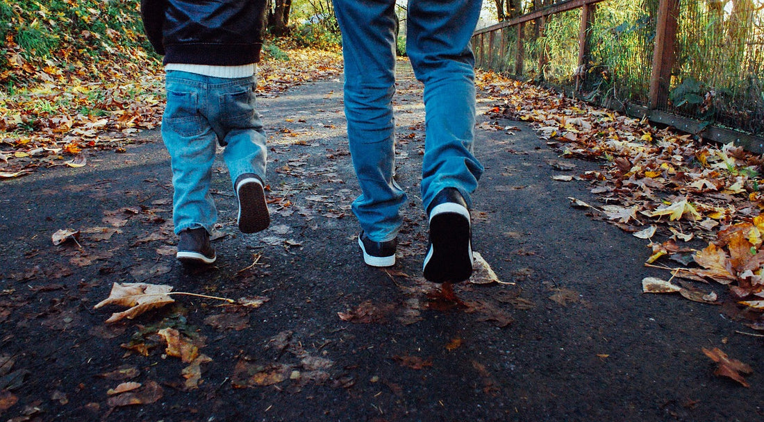 a father and son walking in matching outfits