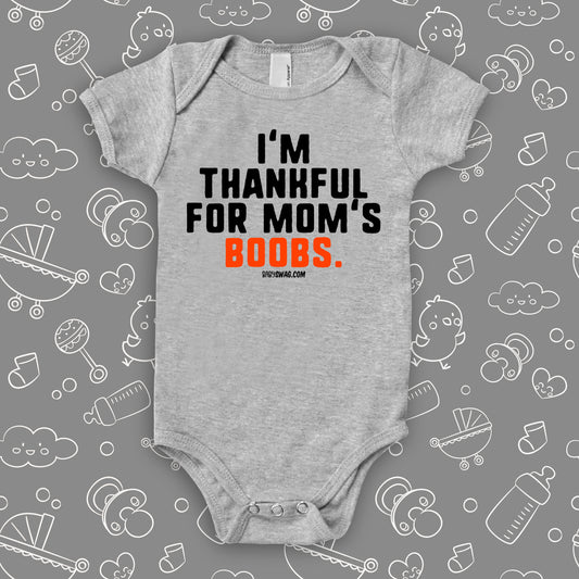 Hilarious baby onesie with saying "I'm Thankful For Mom's Boobs" in grey.