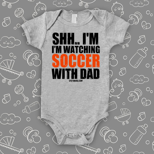 baby boy onesies with saying "Shh... I'm Watching Soccer With Dad" in grey.
