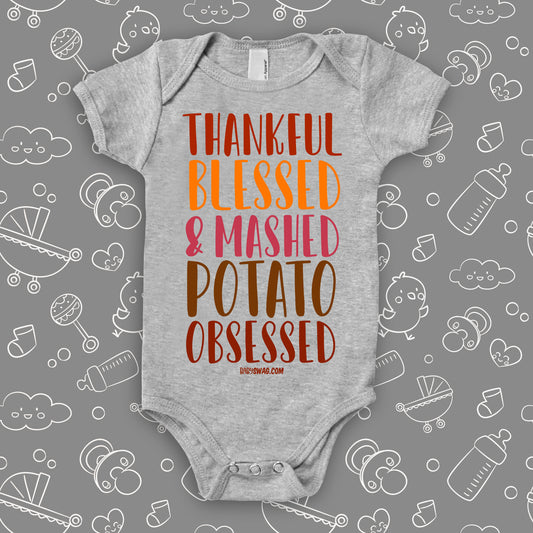 Funny baby onesies with saying "Thankful, Blessed & Mashed Potato Obsessed" in grey.
