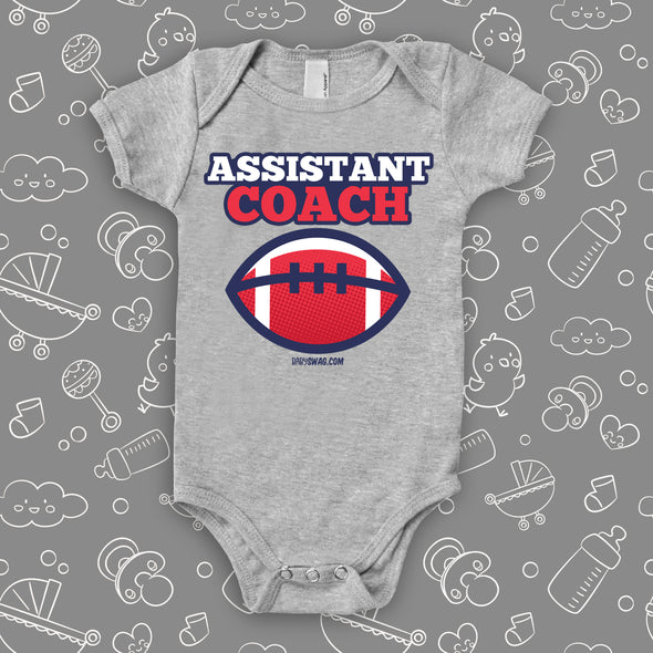 Cool baby boy onesie saying "Assistant coach", in grey.