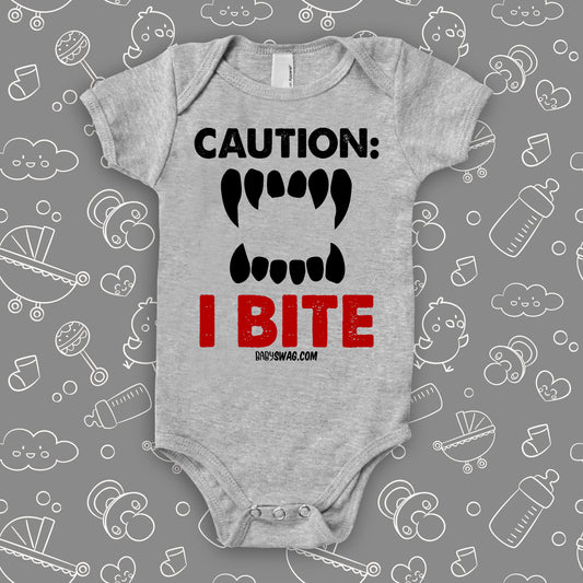 Funny baby onesie saying "Caution: I bite" with an image of scary teeth, color grey.