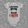 Funny baby onesie saying "Caution: I bite" with an image of scary teeth, color grey. 