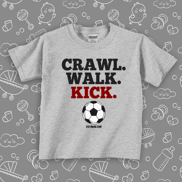 Toddler shirt with saying "Crawl. Walk. Kick." in grey. 