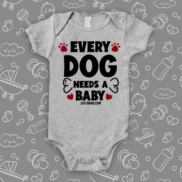 Grey cute baby onesie saying "Every dog needs a baby", red paws and bone also printed.
