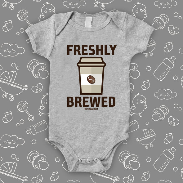 Grey cool baby onesie with "Freshly brewed" print and an image of a coffee-to-go cup. 