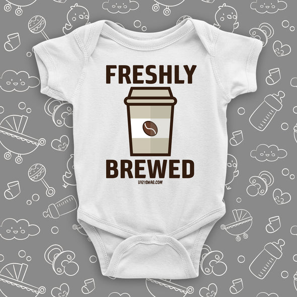 White cool baby onesie with "Freshly brewed" print and an image of a coffee-to-go cup.