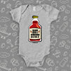 Grey cute baby onesie with a bottle of red sauce labeled "Hot stuff".  