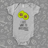 Grey cute baby onesie with an image of two halves of avocado and saying: "I just want to avocuddle"