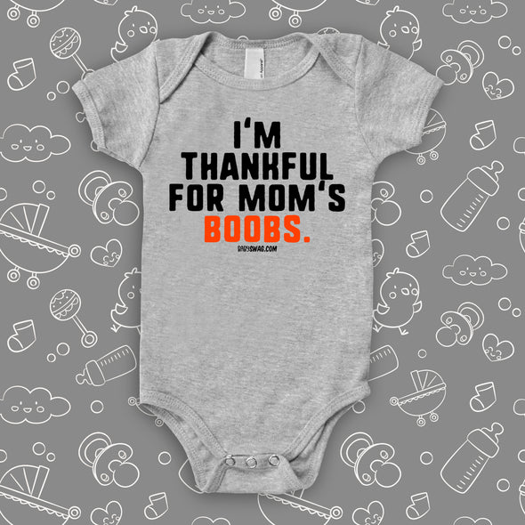 Hilarious baby onesie with saying "I'm Thankful For Mom's Boobs" in grey. 