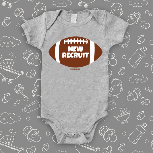 Funny baby boy onesie with a picture of a football and "New Recruit" print, color grey.