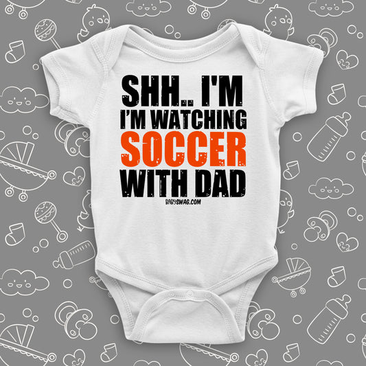 Baby boy onesies with saying "Shh... I'm Wathing Soccer With Dad" in white.